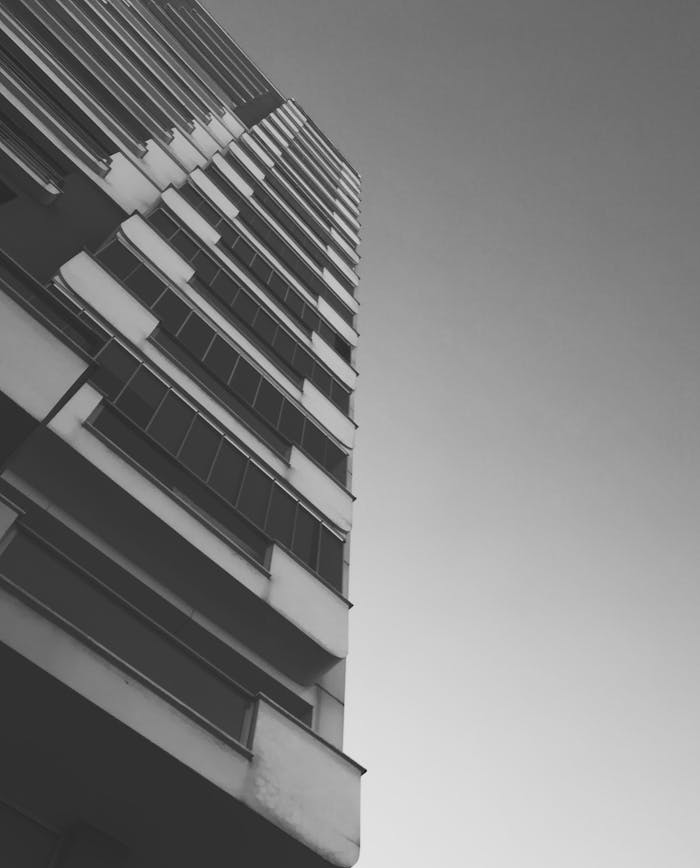 Dramatic grayscale low angle shot of a high-rise building facade emphasizing architectural design.